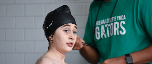 Image of middle-school aged male swimmer and parent standing behind in green Thelma Lovette t-shirt