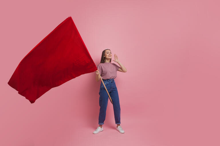 Young and beautiful girl with a red flag on a pink background. A socially active woman, to protest and fight for rights ,the concept